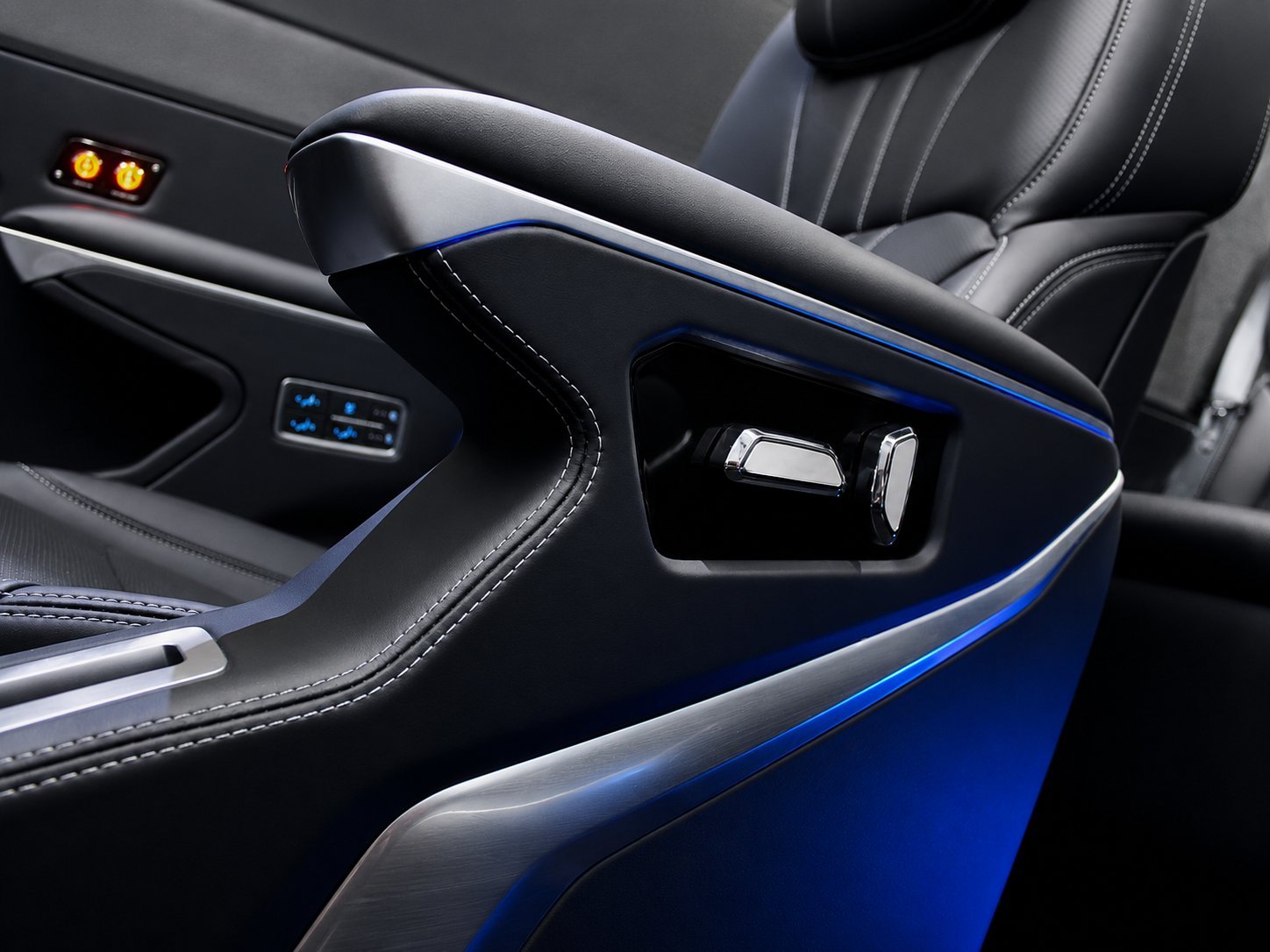 Luxury car interior detail showing leather armrest with blue trim accent and door handle storage compartment