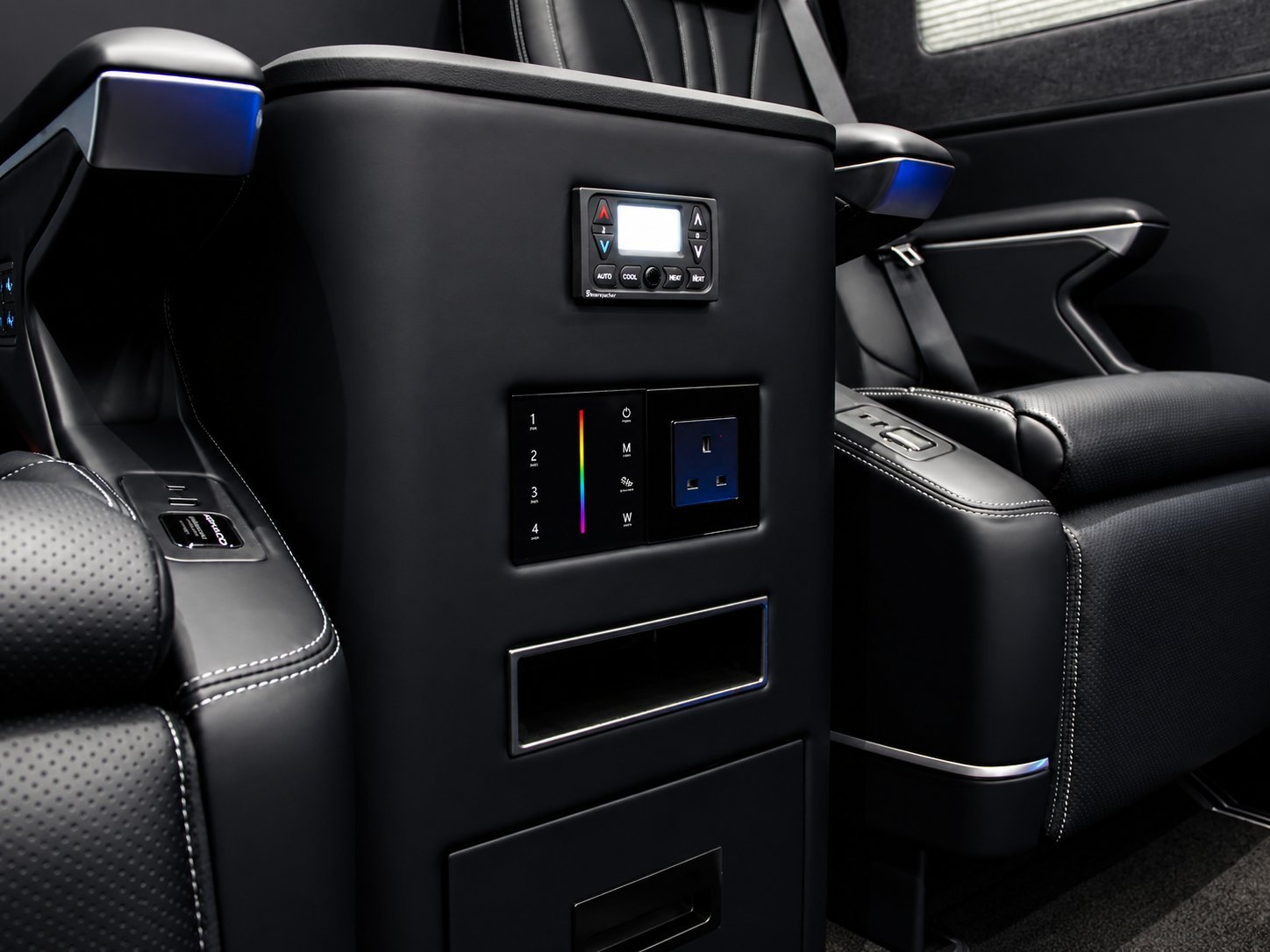 Luxury car interior rear seat console with control panel, illuminated buttons, small display screen, and black leather seating